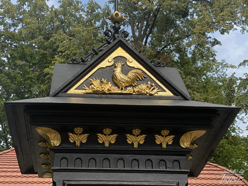Fotografia przedstawia ozdobne zwieńczenie stacji pogodowej przed Pijalnią wód mineralnych w Goczałkowicach-Zdroju. Historia goczałkowickiego uzdrowiska w sięga 1856 roku, kiedy odkryto złoże solanki. Cztery lata później powstały pierwsze obiekty: Dom Zdrojowy, małe łazienki, Pijalnia wód leczniczych oraz pensjonat.