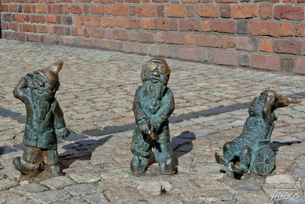 Fotografia przedstawia trzy krasnale „Ślepaka”, „Głuchaka” i „W-Skersa”, na szlaku wrocławskich krasnali
